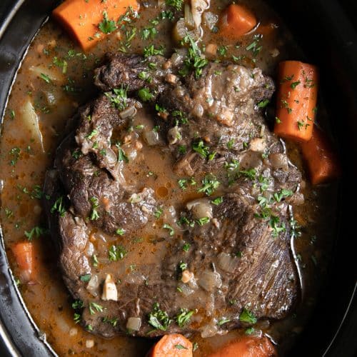 A slow cooker filled with meat and vegetables