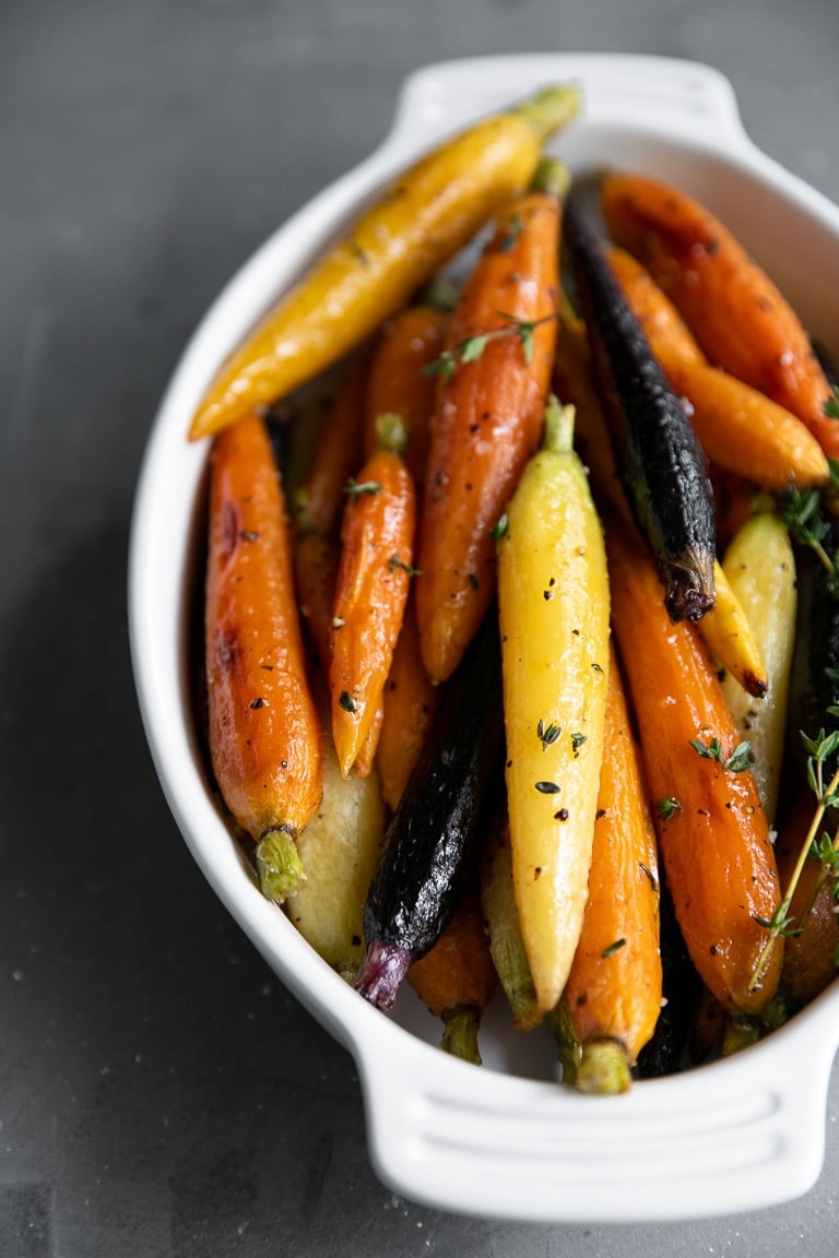 Honey glazed carrots fully cooked and placed in a white baking dish.