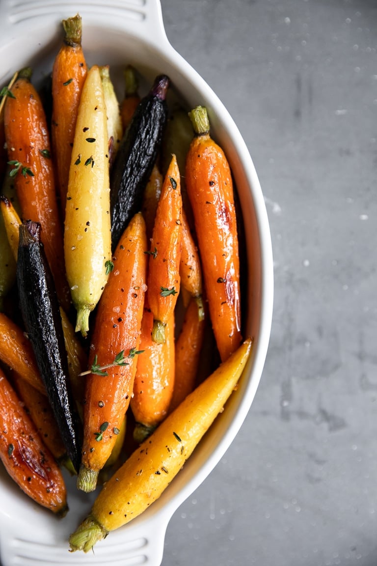 White serving dish filled with petit rainbow honey glazed carrots.