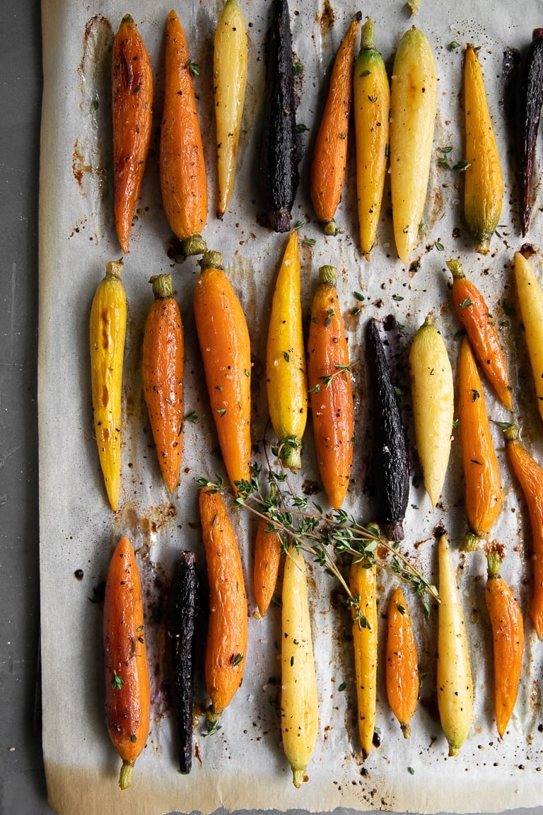 Fully cooked glazed rainbow carrots on a baking sheet.