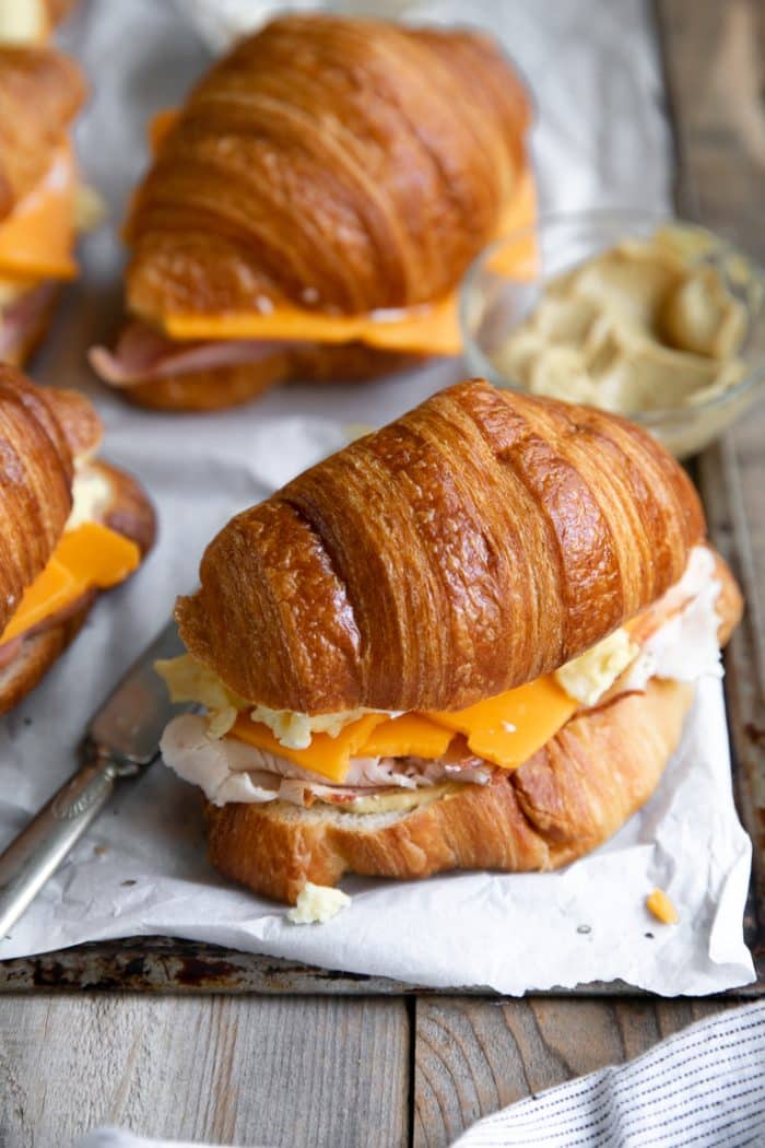Croissant sandwich filled with cooked eggs, sliced cheddar cheese, and sliced ham.