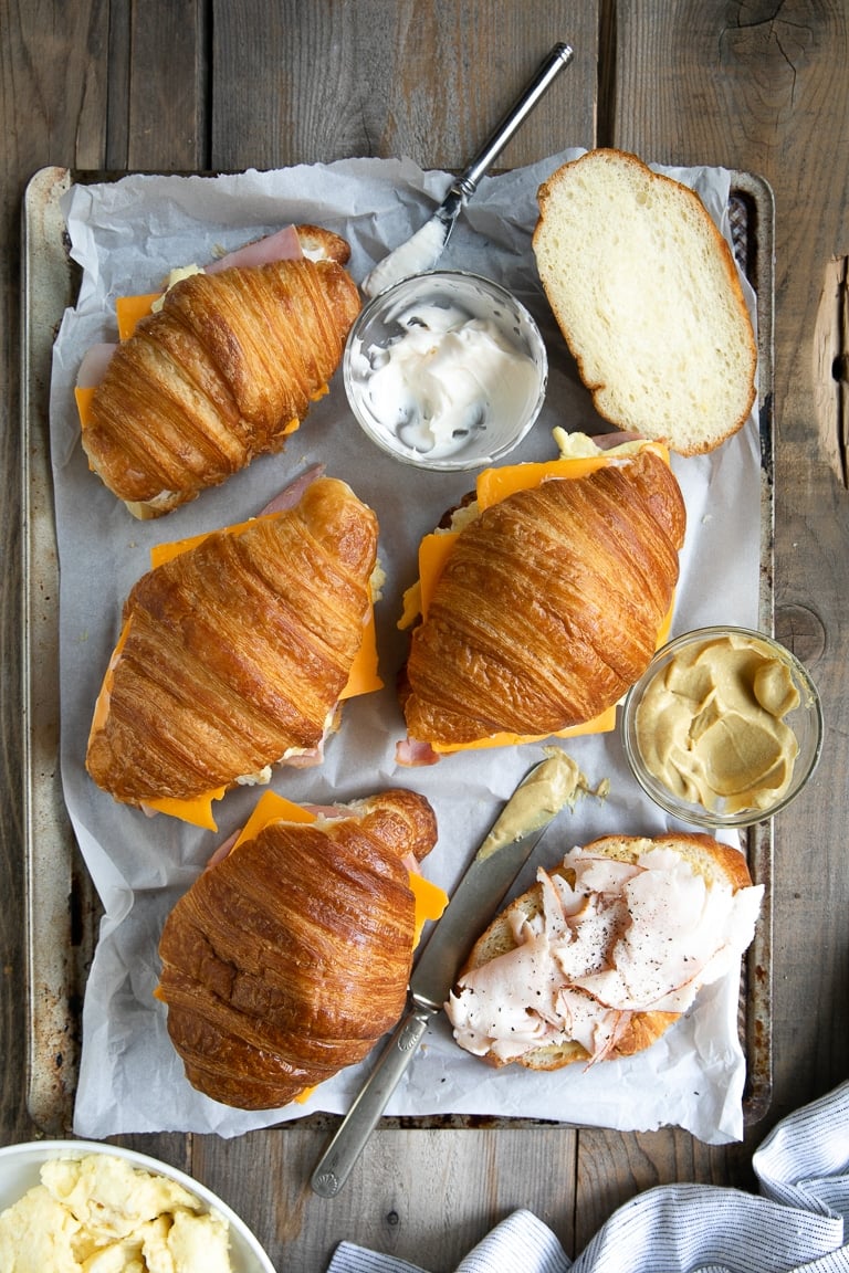 Overhead image of breakfast sandwiches being assembled on a large baking sheet.