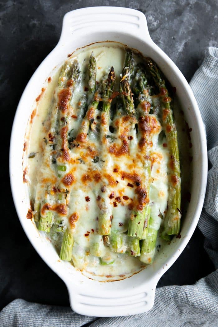 Cheesy Baked Asparagus Gratin in a white oval baking dish.