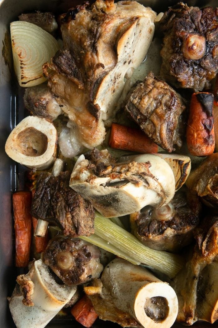 Roasted beef bones and vegetables in a large roasting pan