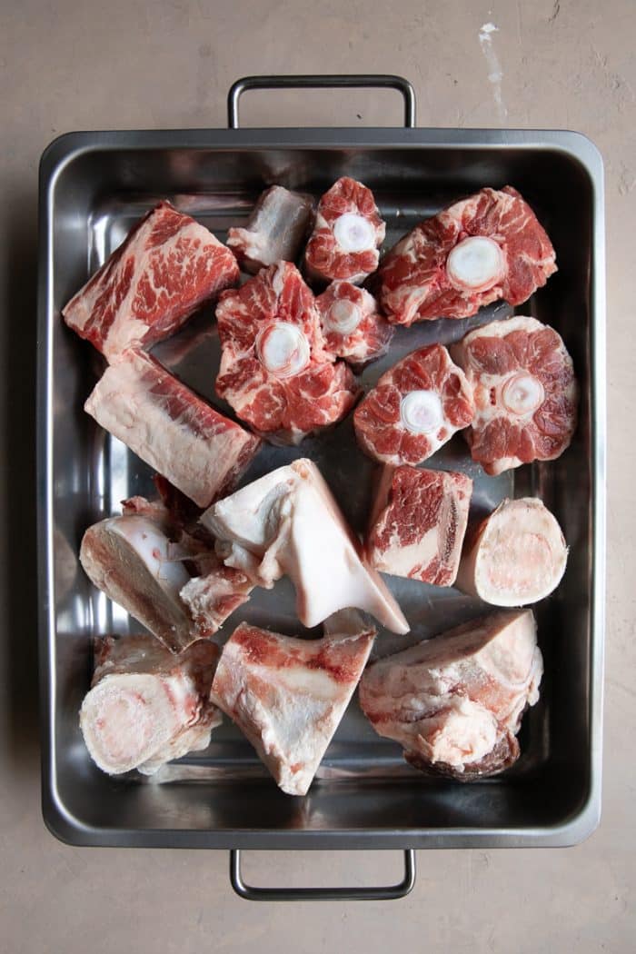 Roasting pan filled with blanched beef bones before roasting.