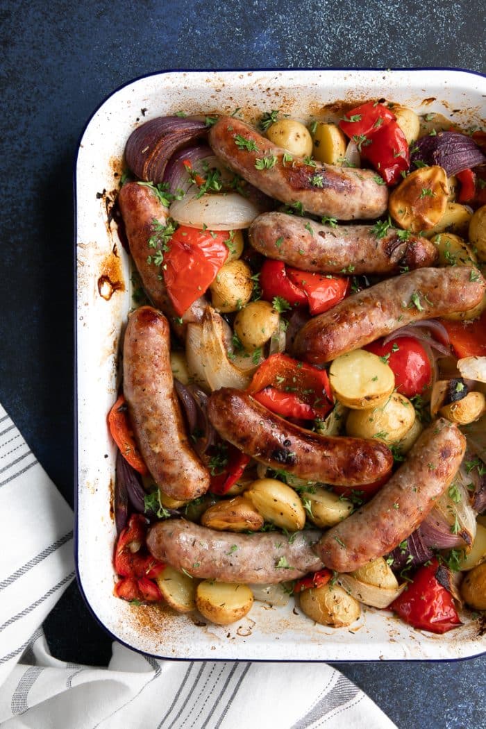 Roasting pan filled with cooked sausage, potatoes, bell pepper, and onions.