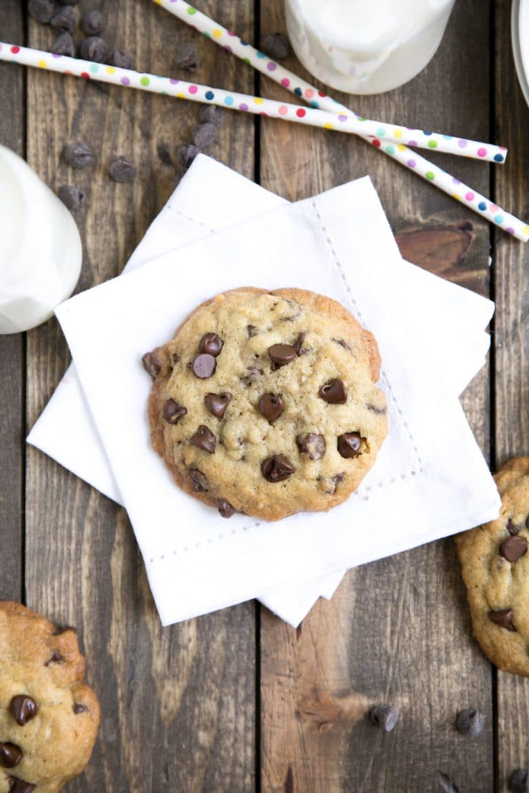 Chocolate chip cookie on white linen napkin with milk.