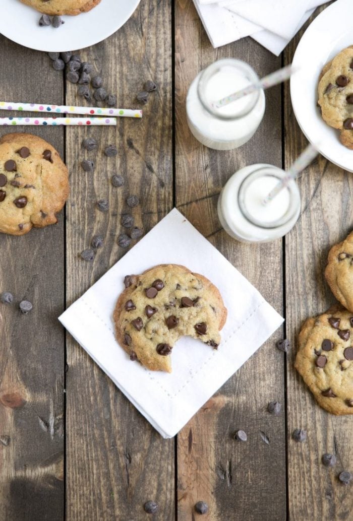 Chocolate chip cookies made with brown butter on a wood table set with milk.