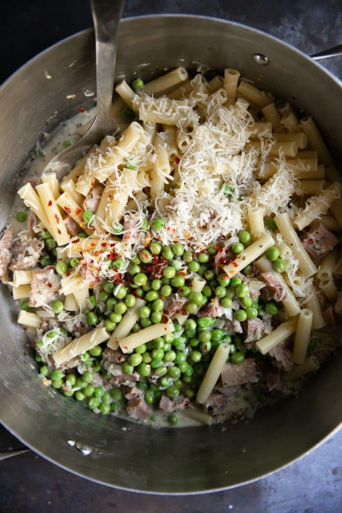Large pot filled with cooked Ziti, a light parmesan cream sauce, peas, crushed red chili flakes, and leftover holiday ham.