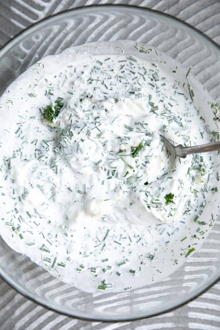 Homemade ranch dressing being mixed together in a glass bowl.