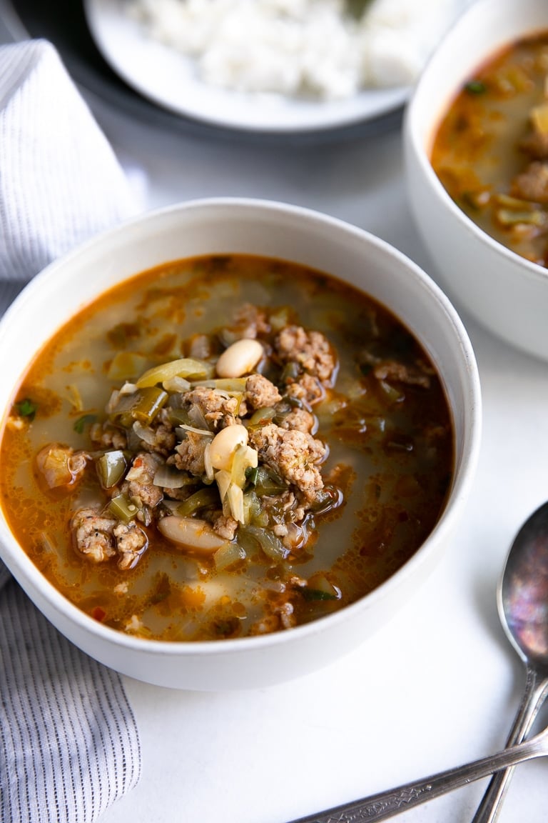 White bowls filled with pork green chili and cannellini beans.