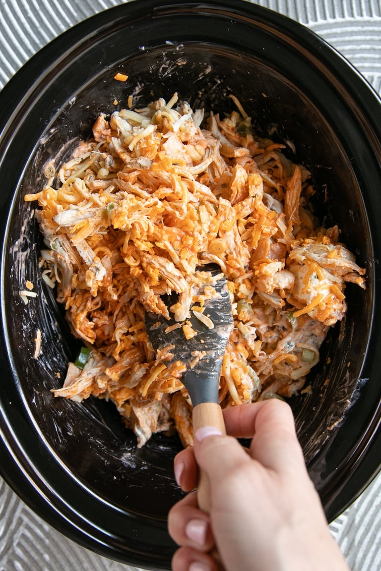 Slow cooker buffalo chicken dip ingredients mixed together in a slow cooker.