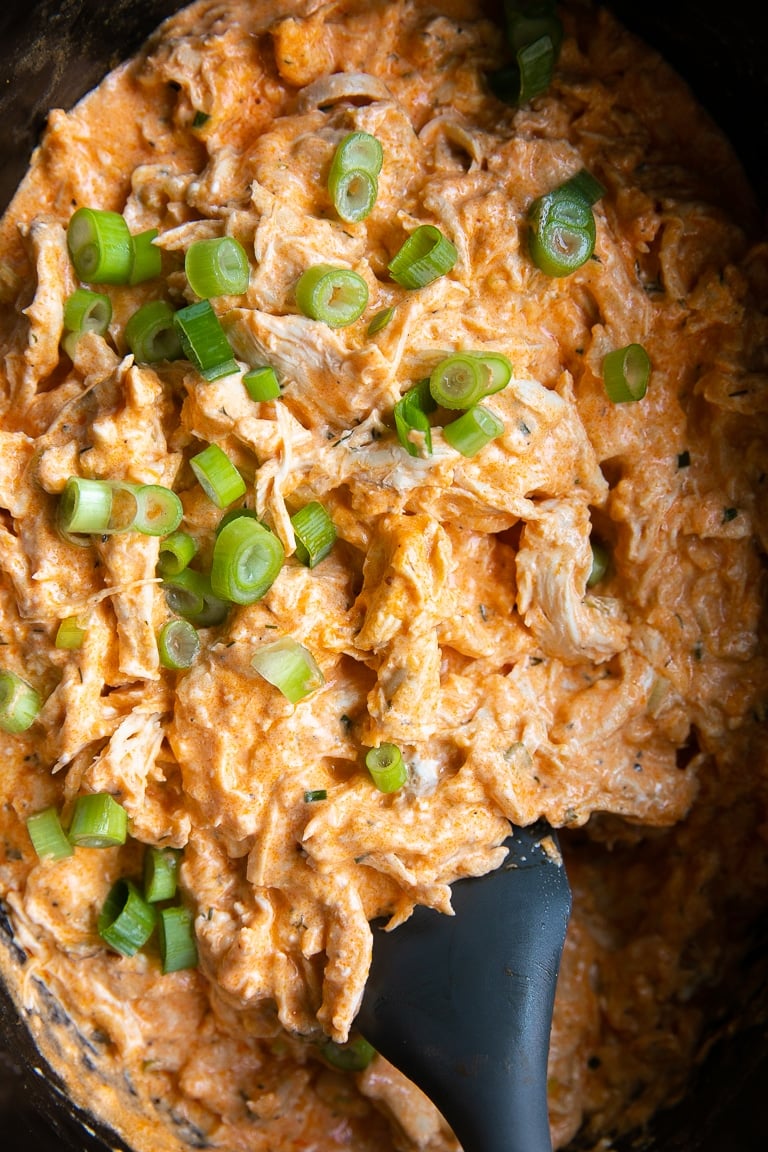 Fully cooked crock pot buffalo chicken dip topped with green onion.