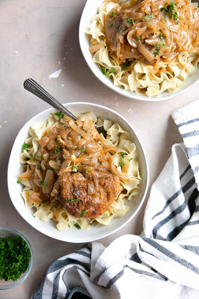 Two white bowls filled with egg noodles smothered in cooked chicken paprikash.