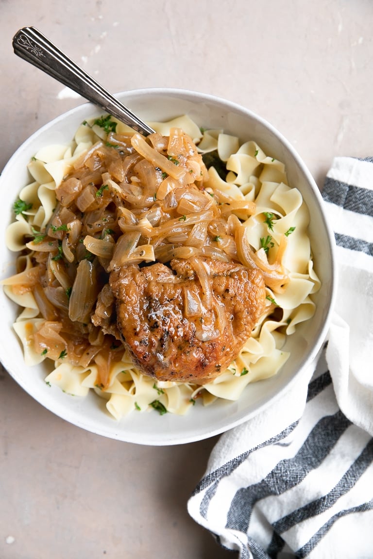 Overhead image of bowl filled with Hungarian Chicken Paprikash with egg noodles and garnished with chopped fresh parsley.