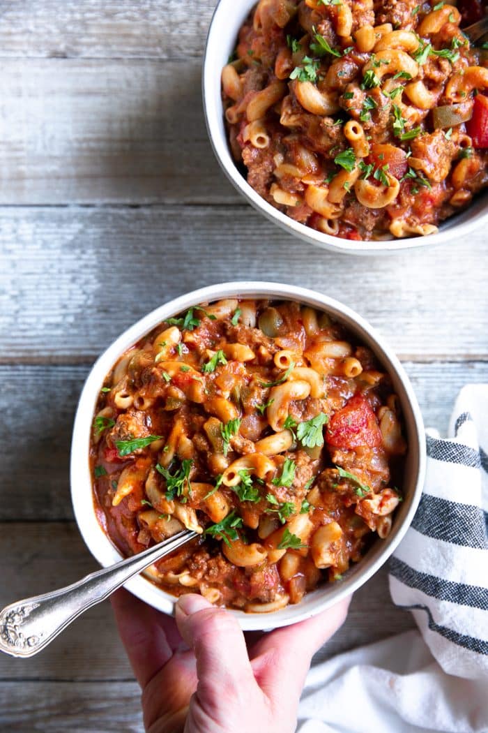 Two white bowls filled with American Goulash made with ground beef, tomatoes, and elbow macaroni.