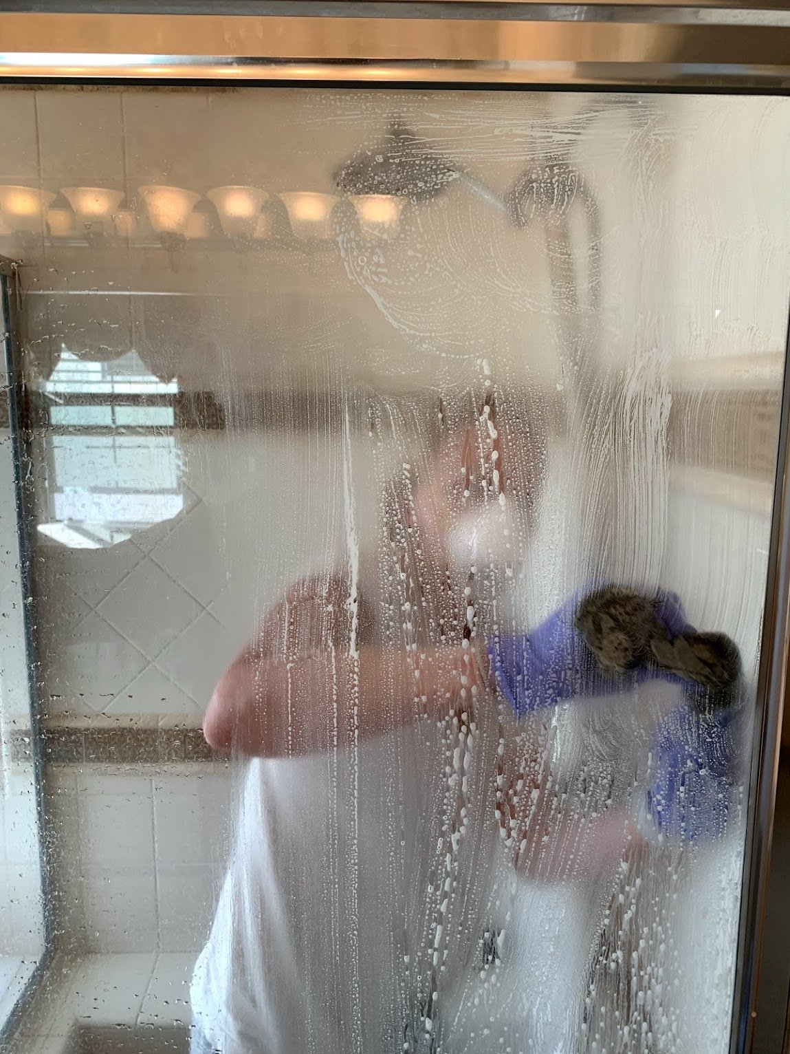 bar keepers friend being applied to shower door covered in hard water stains