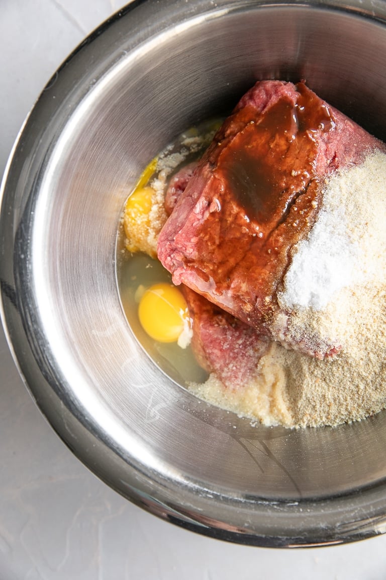 Large mixing bowl filled with ground beef, eggs, and breadcrumbs.