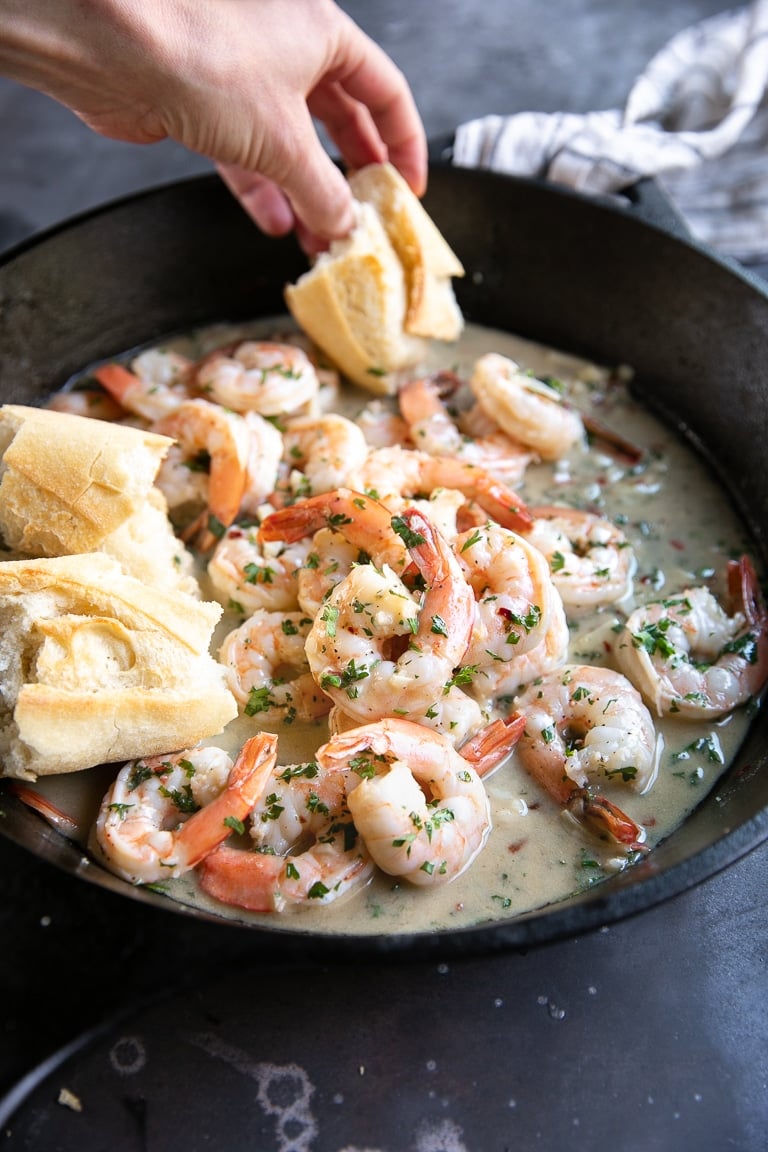 Black cast iron skillet filled with prepared shrimp scampi in a garlic butter sauce.