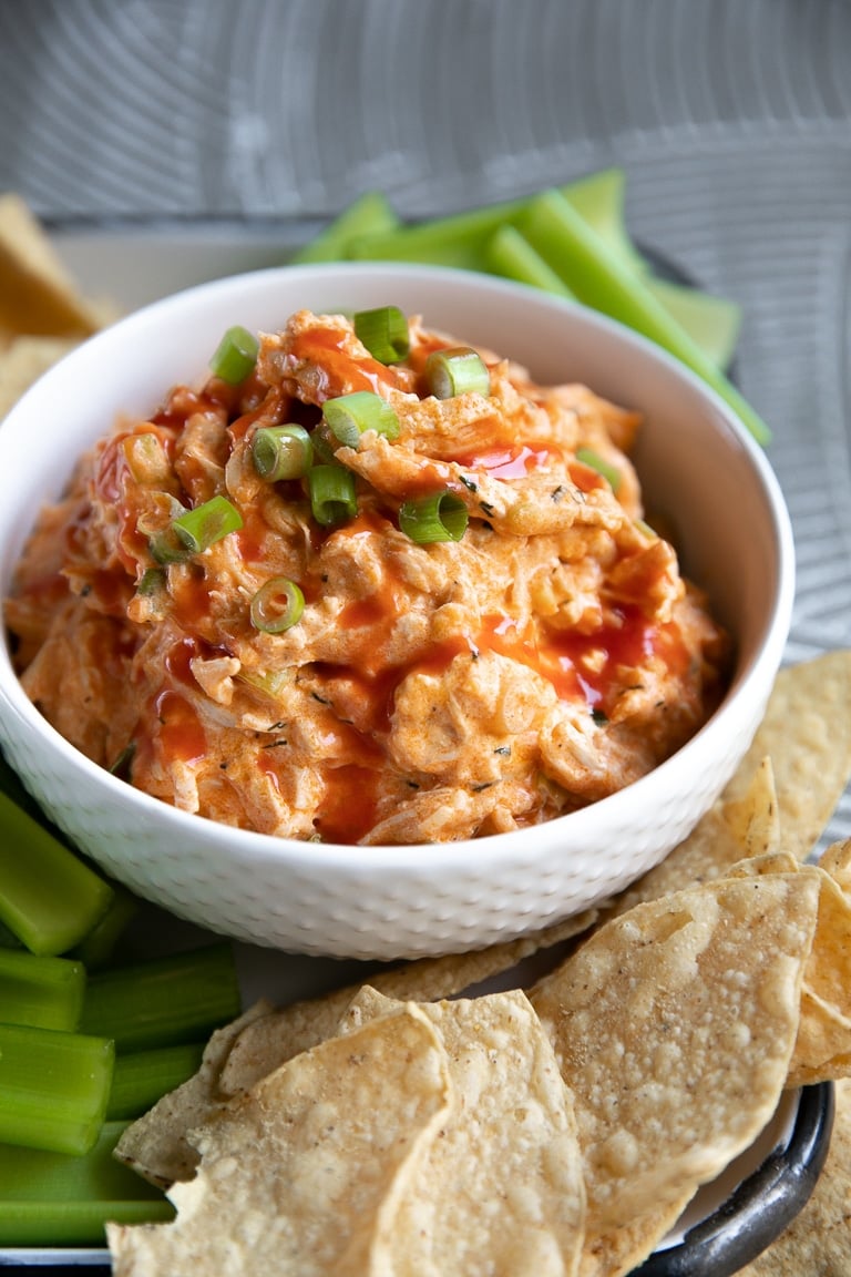 Cheesy slow cooker buffalo chicken dip served with celery and tortilla chips.