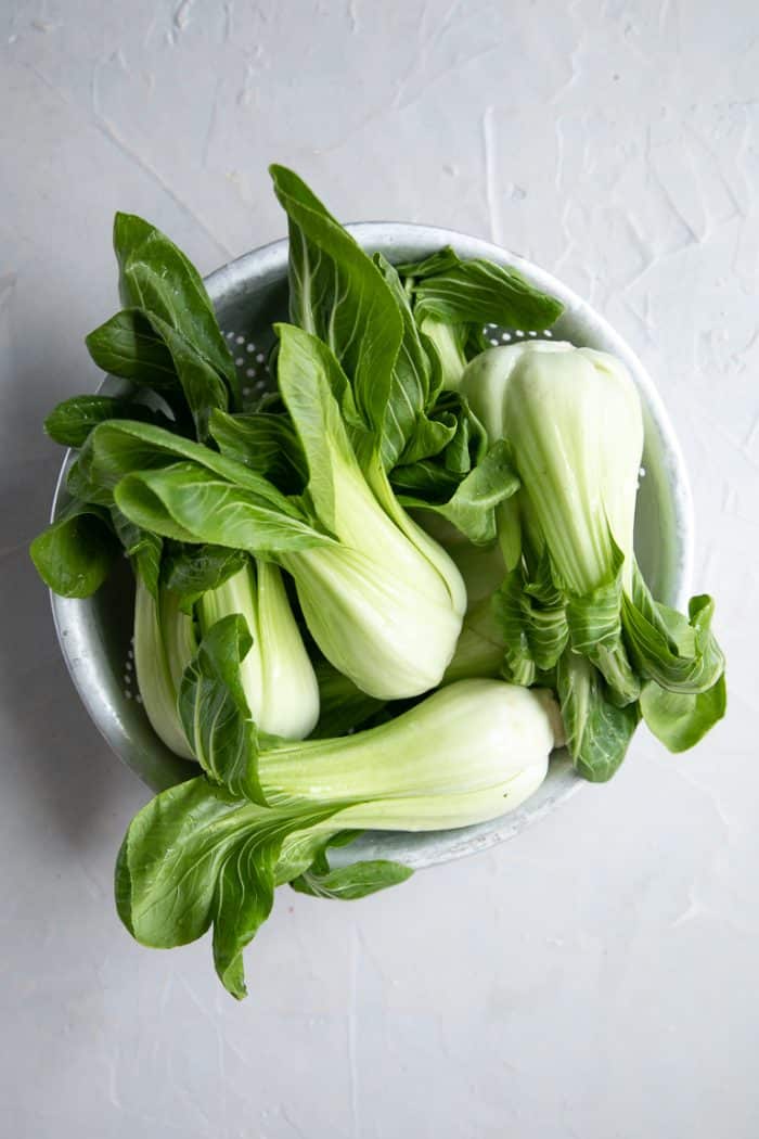 Raw baby bok choy in an old antique tin strainer.