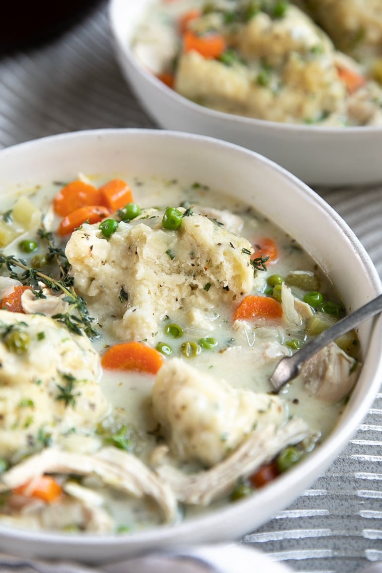 Bowl of chicken and dumplings filled with carrots and big, fluffy drop biscuits.