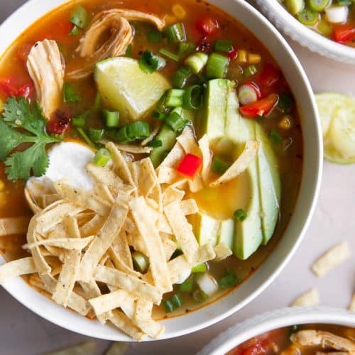 A bowl of food on a plate, with Chicken Tortilla Soup