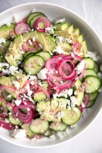 A bowl of salad on a plate, with Cucumber salad