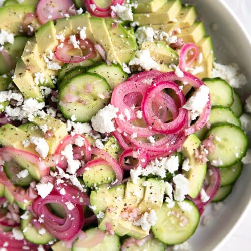 A bowl of salad on a plate, with Cucumber salad