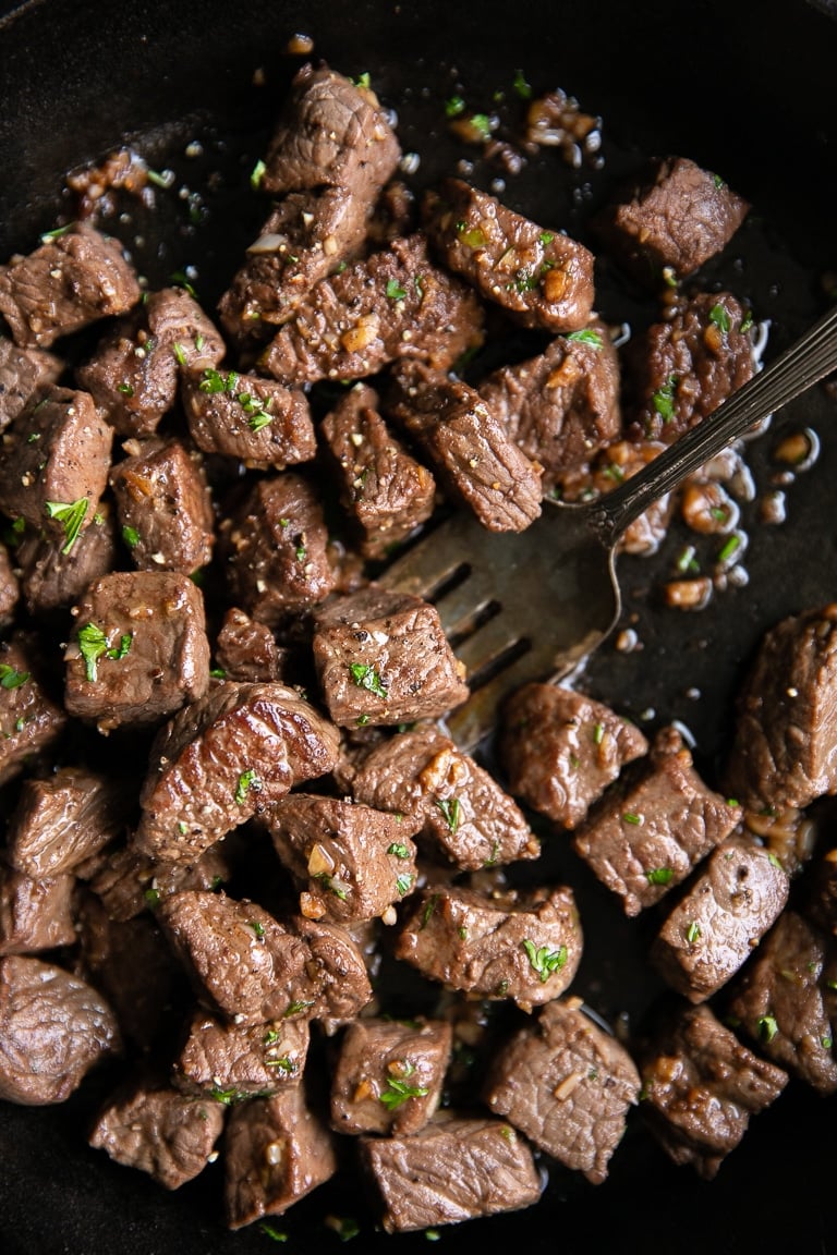 Cooked garlic butter steak bites in a cast iron skillet.