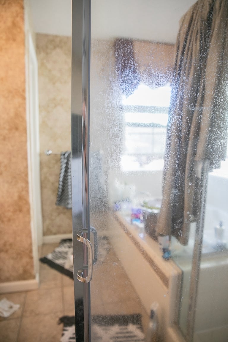 Thick hard water build-up on a glass shower door