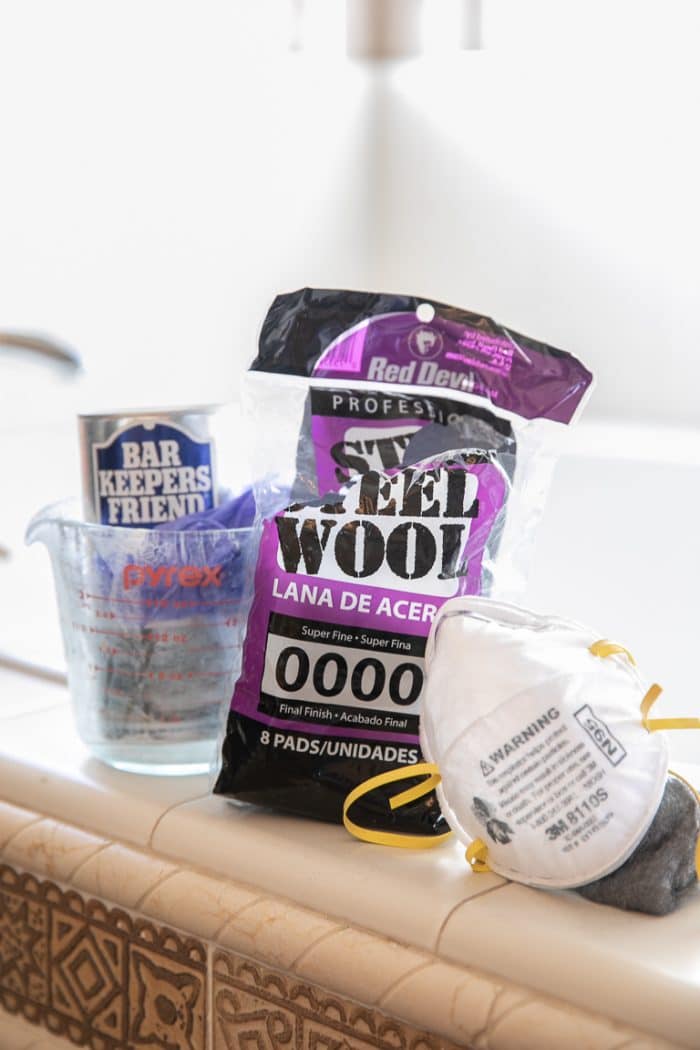 Supplies needed to clean glass shower doors- Bar Keepers Friends, gloves, 0000 Super Fine Steel Wool, and a mask.