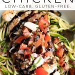 Overhead shot of a white bowl filled with grilled bruschetta chicken served on a bed of zucchini noodles, topped with fresh tomato basil bruschetta and balsamic glaze. The image has a bold white overlay with the text "THEFORKEDSPOON.COM Bruschetta Chicken Low-Carb. Gluten-Free." written across the top.