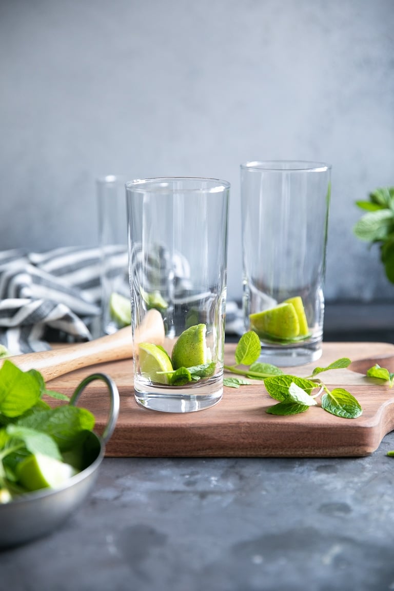 Three highball glasses each filled with two limes and mint leaves.