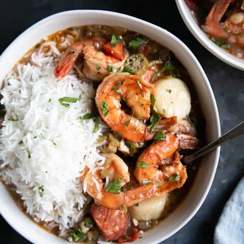 Large white bowl filled with seafood gumbo and white rice.