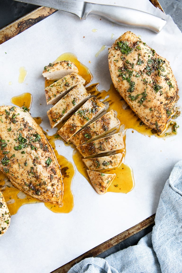 Perfectly baked chicken breasts on a large baking sheet.