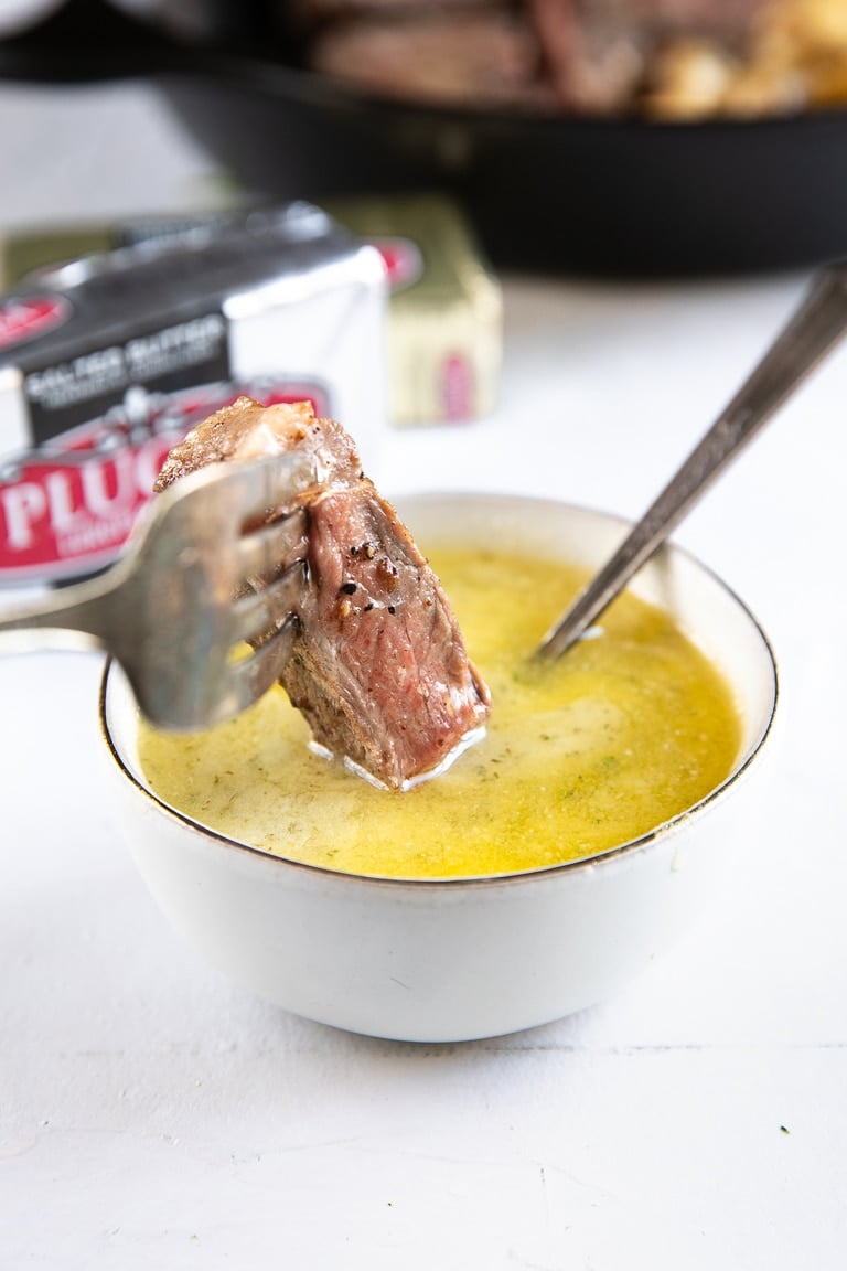 Dipping a piece of steak into garlic butter sauce.