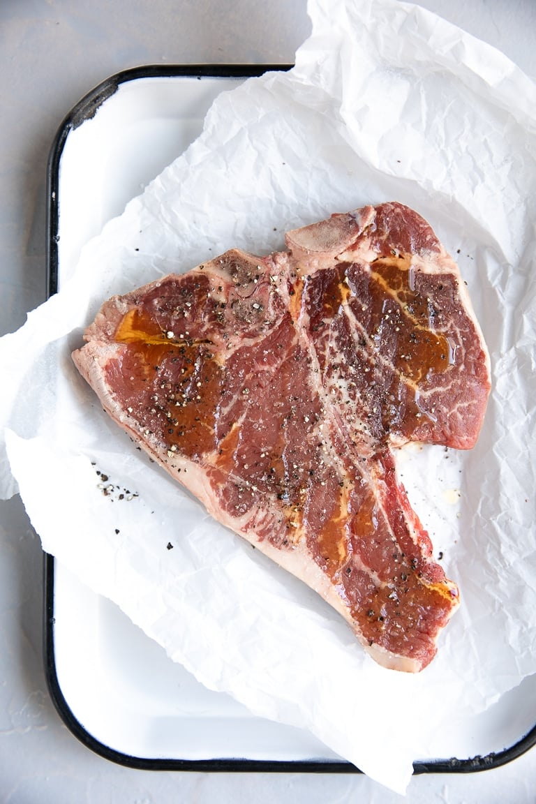 Raw seasoned T-bone steak.