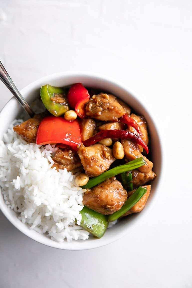 Overhead image of a white bowl filled with white rice and Kung Pao Chicken.