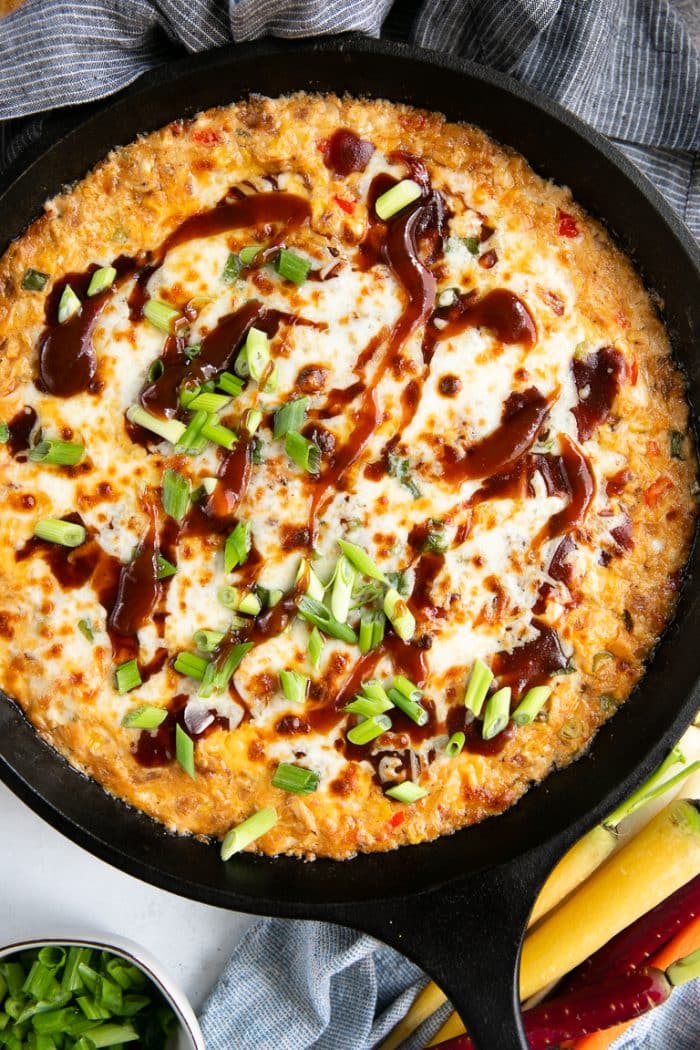 Black bast iron skillet filled with hot and cheesy BBQ chicken dip.