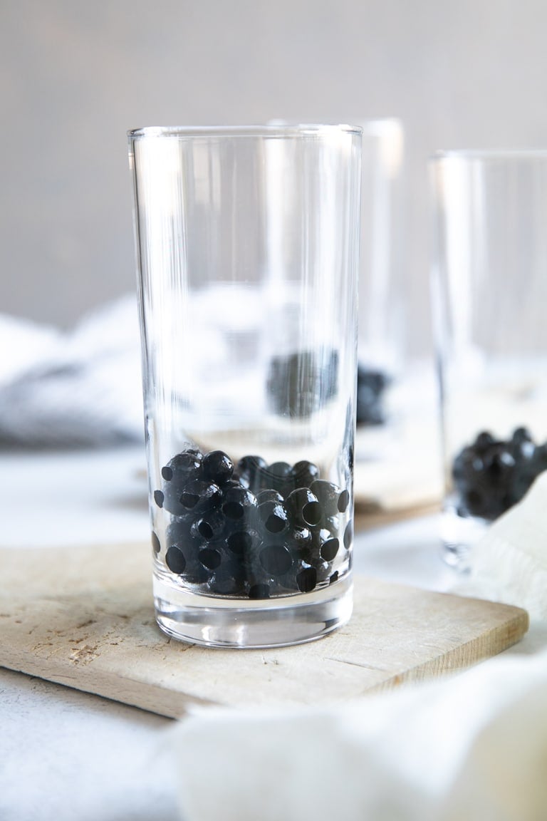 A close up of a glass cup on a counter with tapioca pearls (boba)