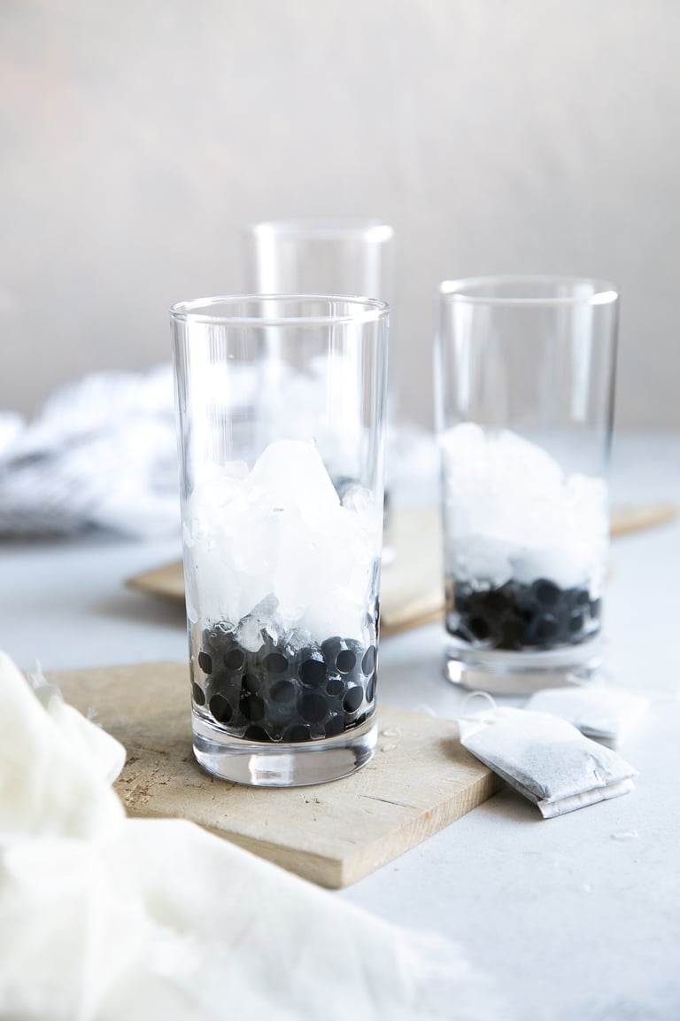 A close up of a glass cup on a counter with tapioca pearls (boba) and ice