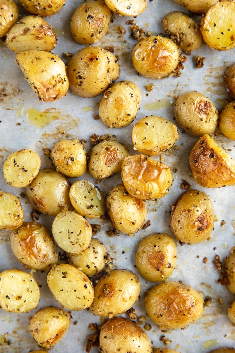 Mini potatoes on a large baking sheet after roasting.