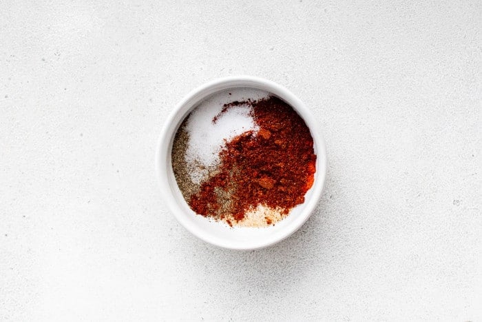 Small white bowl filled with homemade fajita seasoning mix on a white background.