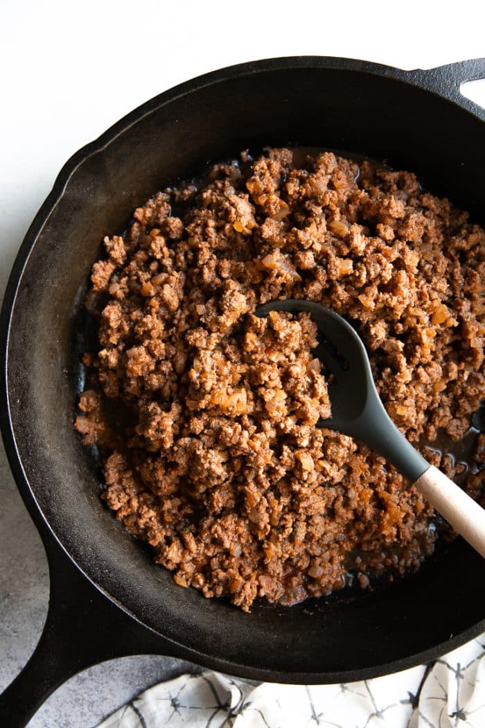 Fully cooked ground beef taco meat in a large black cast iron skillet.