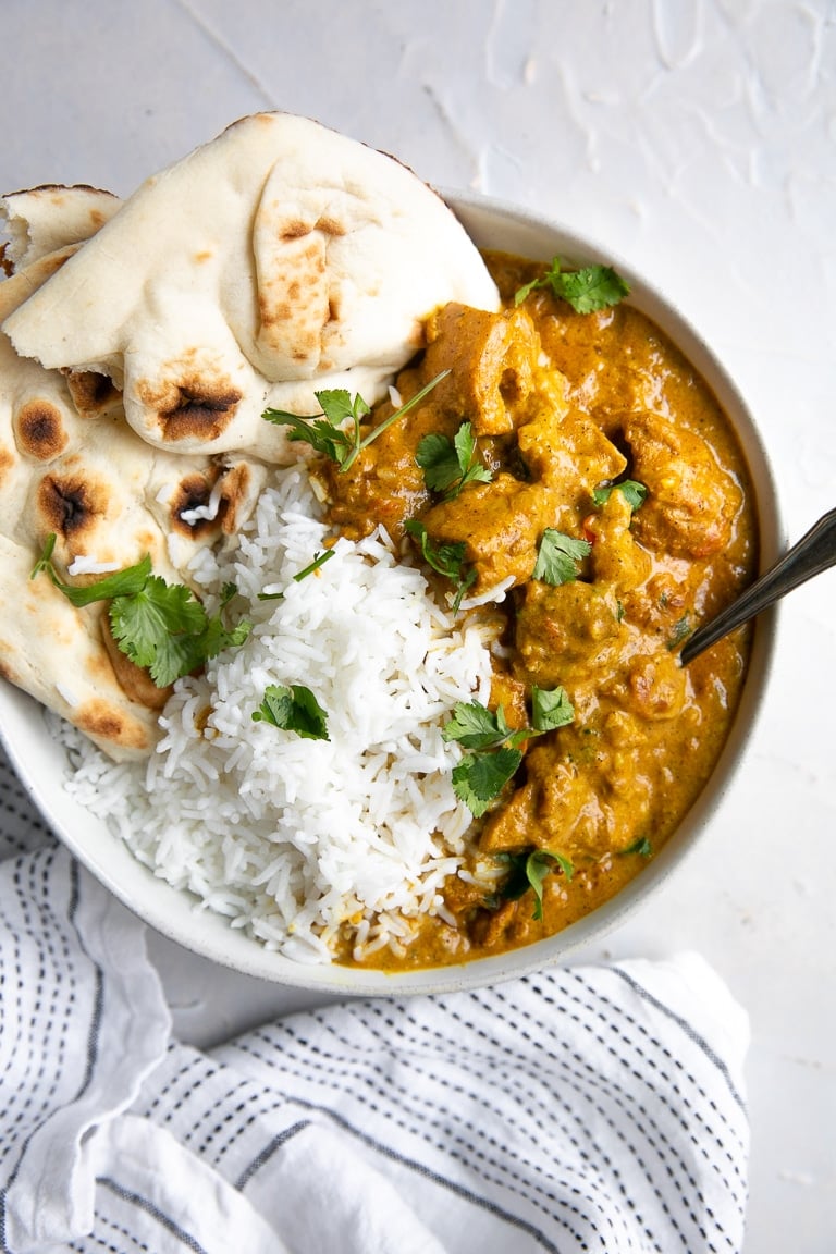 Shallow white bowl filled with creamy butter chicken and rice.