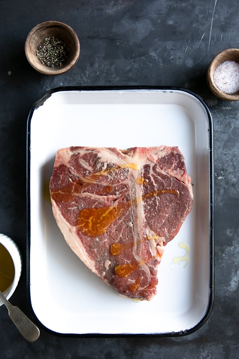 A tray with Steak with olive oil drizzled on steak