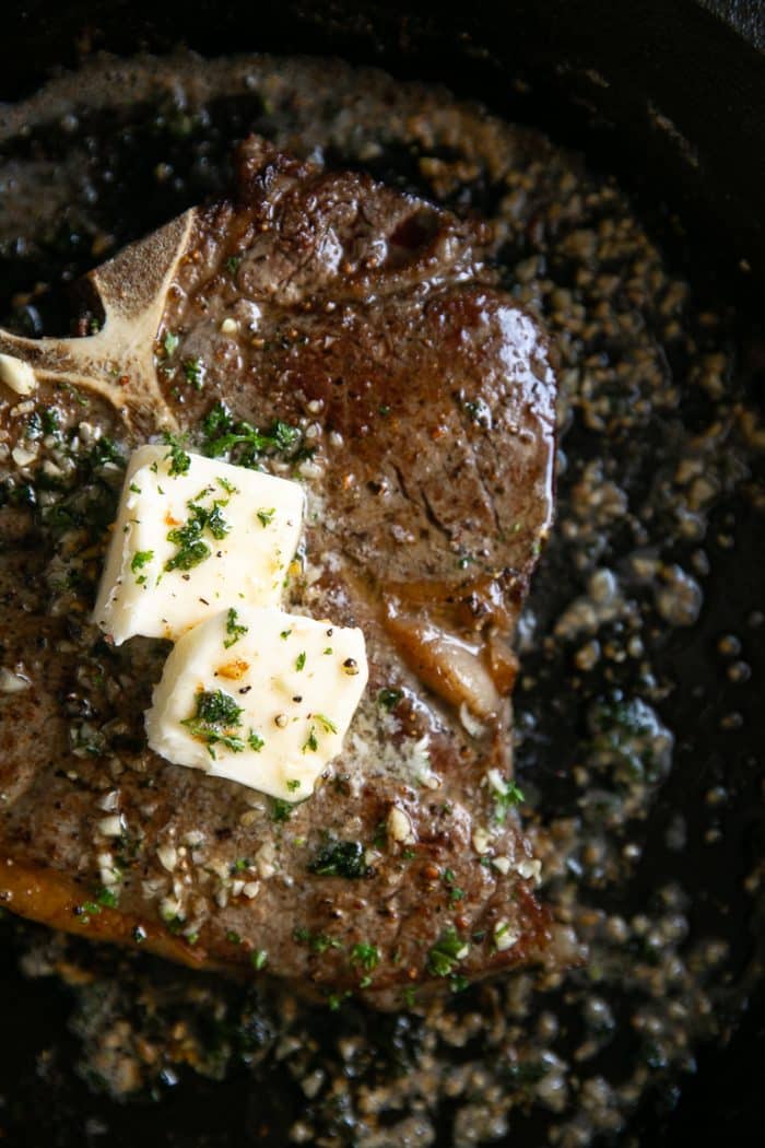 Butter Basted Pan-Seared T-Bone Steak in a cast iron skillet.