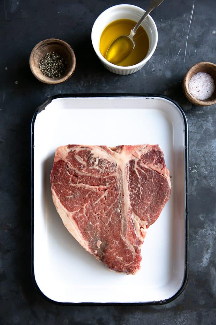 A tray with Steak surrounded by spices