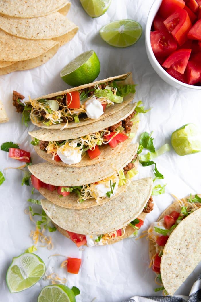 Prepared ground beef tacos filled with shredded lettuce, tomatoes, cheese, and sour cream.